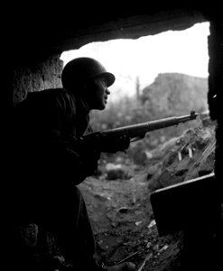 SC 364289 - Pfc. Morton Fernberg, Vineland, N.J., an infantryman with the 13th Regiment, 8th Division, First U.S. Army, takes shelter from a German artillery barrage.