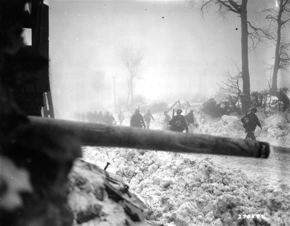 SC 270594 - American infantrymen of the 644th Tank Destroyer Battalion, 2nd Platoon, Co. A, 2nd Division, pass a tank destroyer as they move through heavy fog and rain into the town of Krinkelt, Belgium.