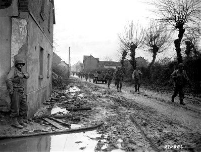 SC 270886 - American infantrymen of 120th Regiment, 30th Infantry Division, pass through a German village as they move up to the front lines near Warden, Germany. 21 November, 1944.