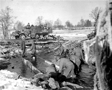 SC 198858 - Combat engineers work in icy waters to build a bridge to speed traffic to the front in the Houffalize sector, Belgium. 15 January, 1945. photo