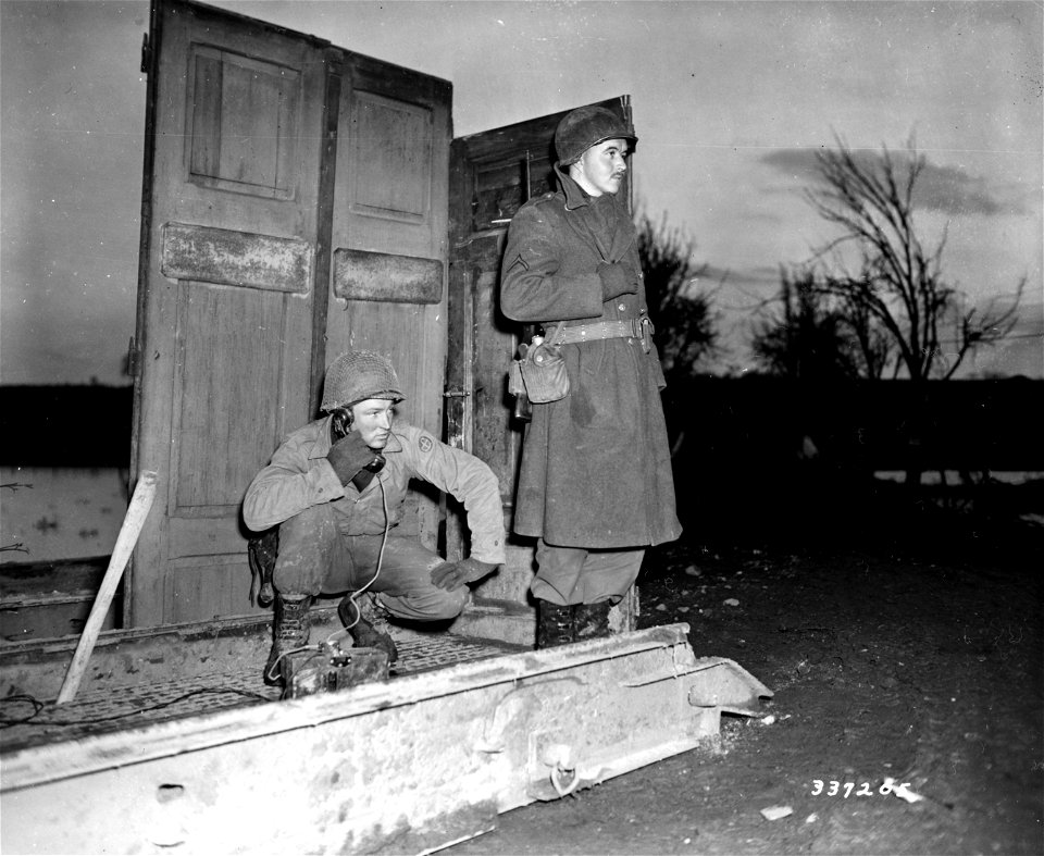 SC 337205 - Pvt. Bill Mels of Sheldon, Iowa, and Pfc. Ben Cole of Forest City, North Carolina, stand guard with an improvised shelter to shield them from the wintry blasts.