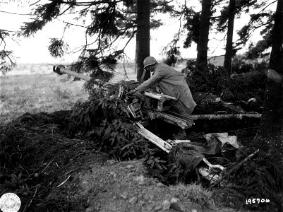 SC 195706 - Emplaced between two pillboxes of the Siegfried Line, this German 88mm gun [sic] was knocked out by Yanks, one of whom examines the smashed piece. 15 September, 1944. photo