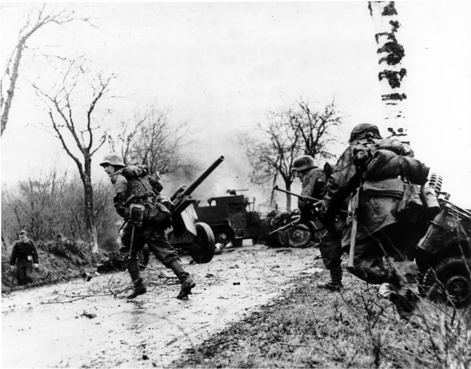 German troops advancing past abandoned American equipment during the Battle of the Bulge