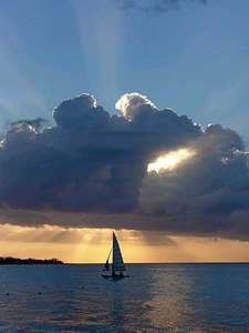 Sailboat under a clump of clouds at sunset in Jamaica photo