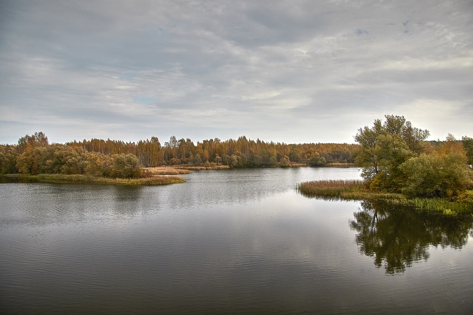 Autumn landscape with lake, trees, and clouds