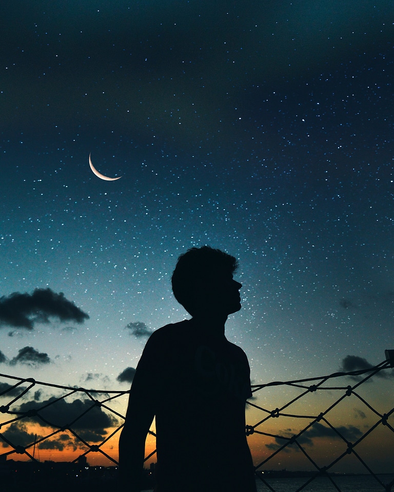 Silhouette of boy looking up at the sky of stars