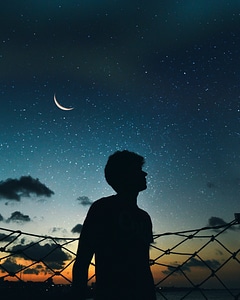 Silhouette of boy looking up at the sky of stars photo