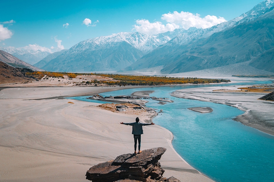 Man standing on a rock overlooking river and landscsape