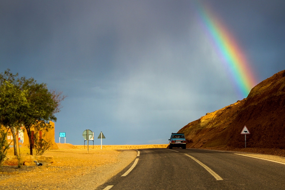 Car Driving into the landscape with a rainbow