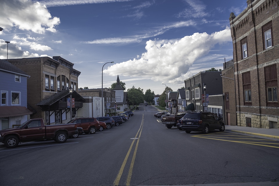 Parked Cars at the sides of the street with clouds in the sky in New Glarus