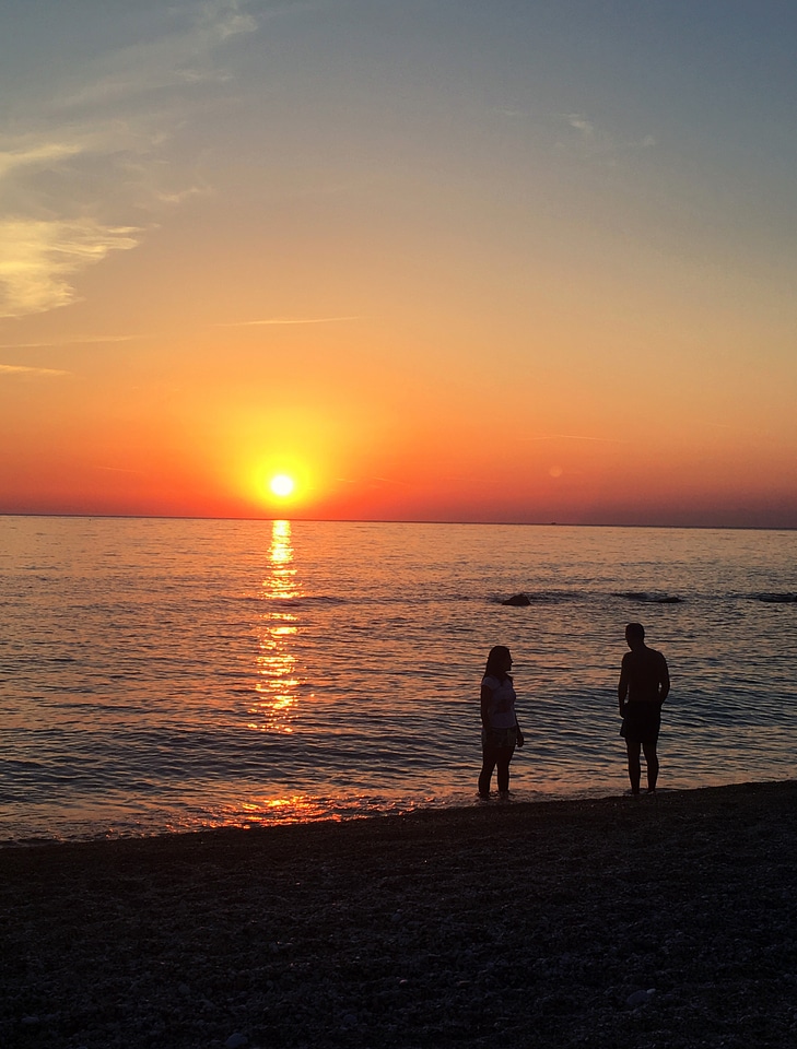 Two people watching sunrise over the ocean