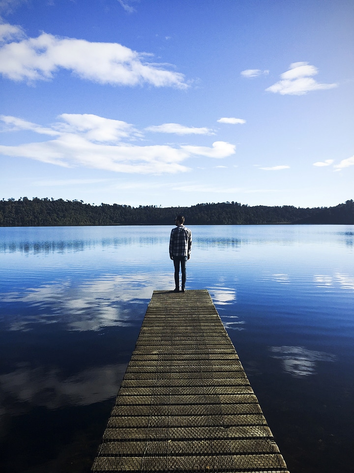 Man standing on the dock looking at the lake landscape photo