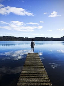 Man standing on the dock looking at the lake landscape photo