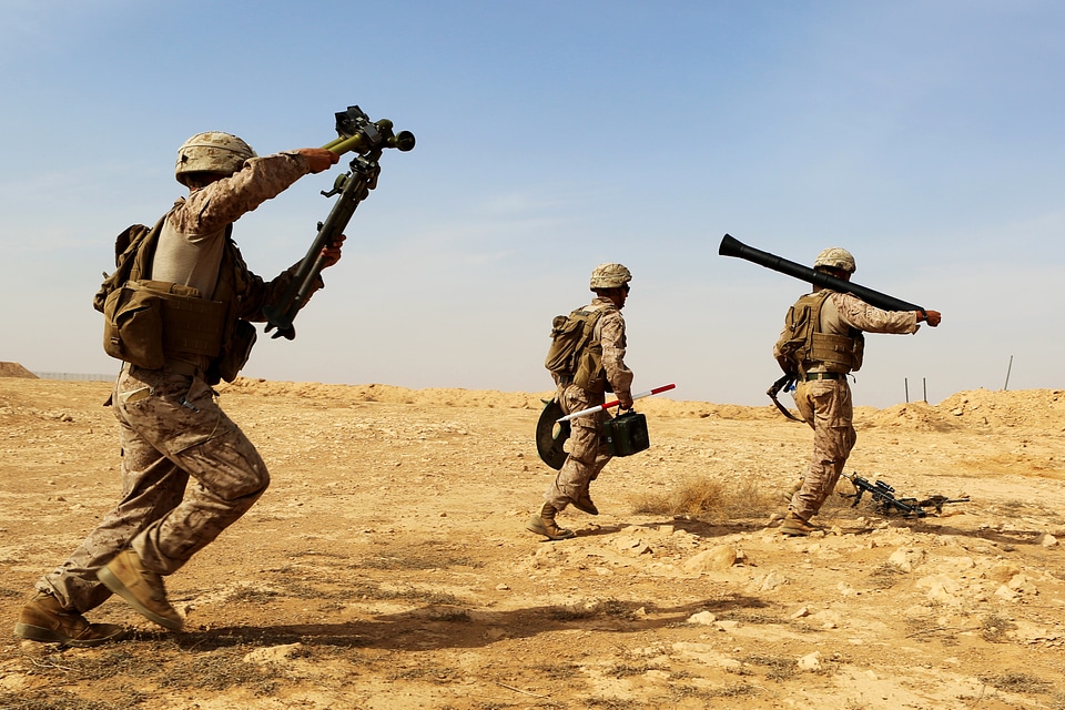 Three US Marines carrying weapons walking across the desert