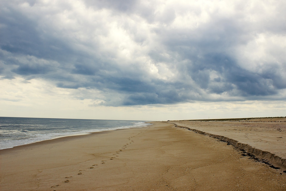 Beach with footsteps in the sand with clouds photo