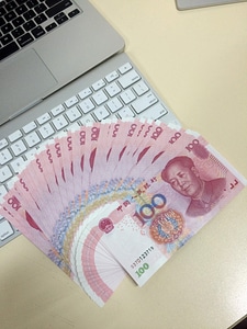 Macbook with a fan of chinese hundred dollar bills photo