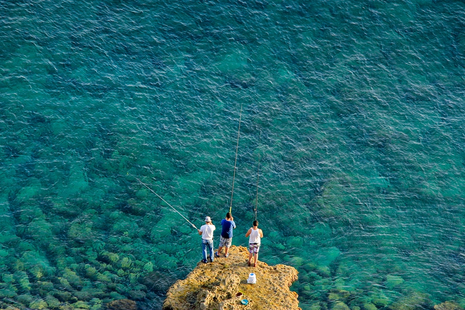 Three people fishing on a rock outcropping