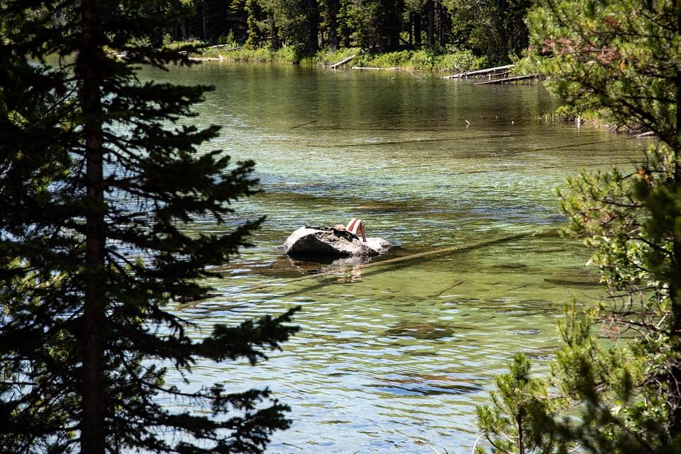 Person sunbathing on Rock in middle of lake