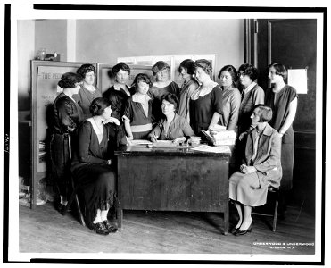 Margaret Sanger, half-length portrait, seated behind desk, surrounded by twelve other women) - Underwood & Underwood Studios, N.Y LCCN93504866