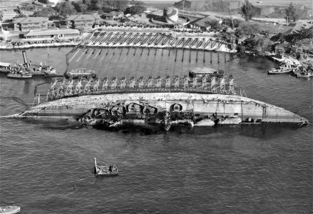 NASPH ^118506- 19 March 1943. USS Oklahoma- Salvage. Aerial view toward shore with ship in 90 degree position. - NARA - 296975 photo