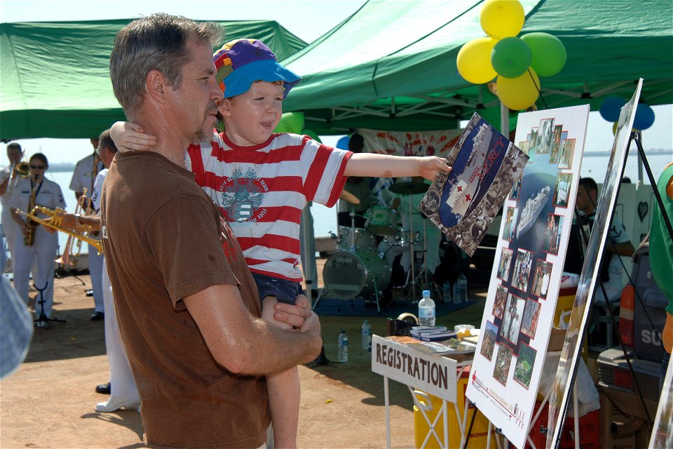 US Navy 060903-N-6501M-002 A father shows his son pictures on a display aboard of the Military Sealift Command hospital ship USNS Mercy (T-AH 19)