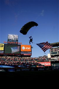 US Navy 090702-N-5366K-231 Chief Special Warfare Operator (SEAL) William Davis, assigned to the U.S. Navy Parachute Team the Leap Frogs, flares his canopy while flying an American flag as he makes his final approach to land