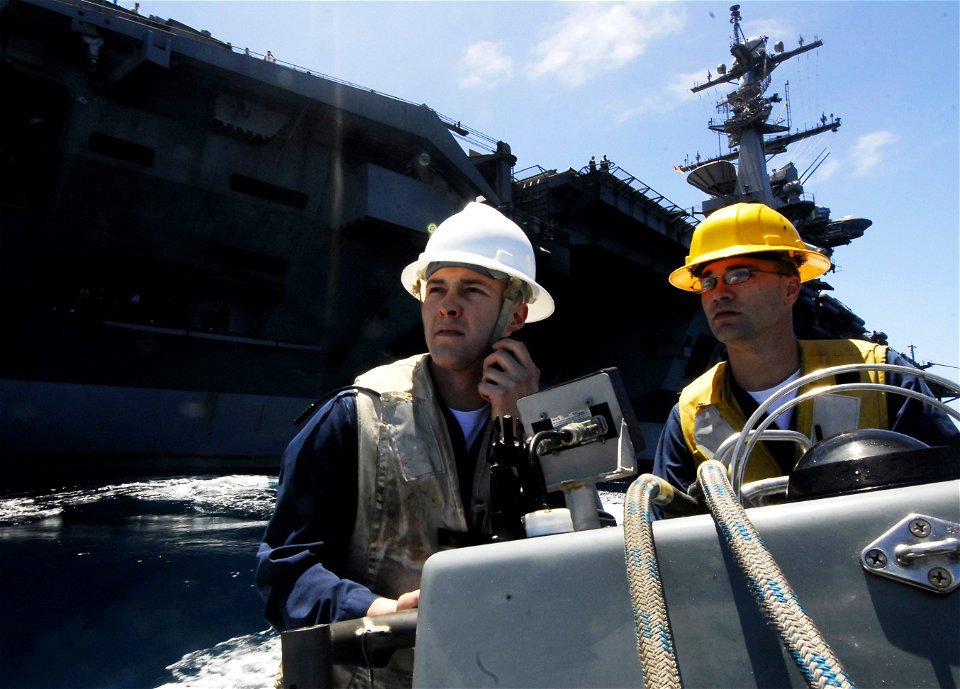 US Navy 090705-N-6538W-252 Officer of the boat Lt j.g. Paul Kaufman, from Roberts, Mont., left, and Boatswain's Mate 2nd Class Chris Boosalis, from Lancaster, Calif., operate a rigid hulled inflatable boat during a man overboar