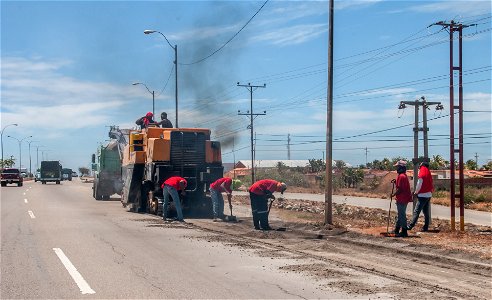 Personas realizando trabajos de reparación de manto asfaltico en la Avenida Juan Bautista