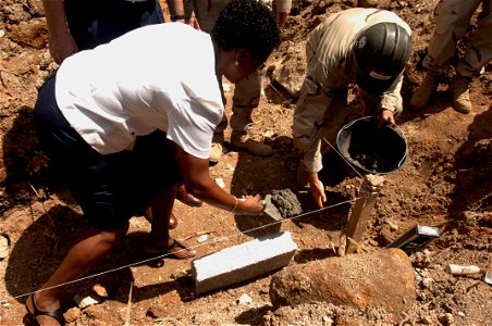 US Navy 061011-F-0929W-051 Dinah Hibonne, the health coordinator of Baie St. Anne Hospital, and Builder 2nd Class Todd Campbell lay mortar for the first stone during a groundbreaking ceremony for a new Baie St. Anne Hospital mo