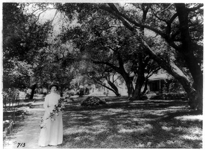 Mme. Helena Modjeska, full-length portrait, standing, facing front, holding flowers outside her home, California LCCN90707248 photo