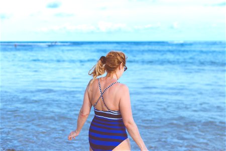 Woman Wearing Blue Monokini Standing Beside Body Of Water Under Blue Sky photo