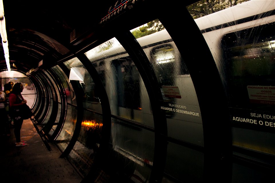 Woman Wearing Pink And Black Scoop-neck T-shirt And Black Pants Standing In Front Of Train In Train Station