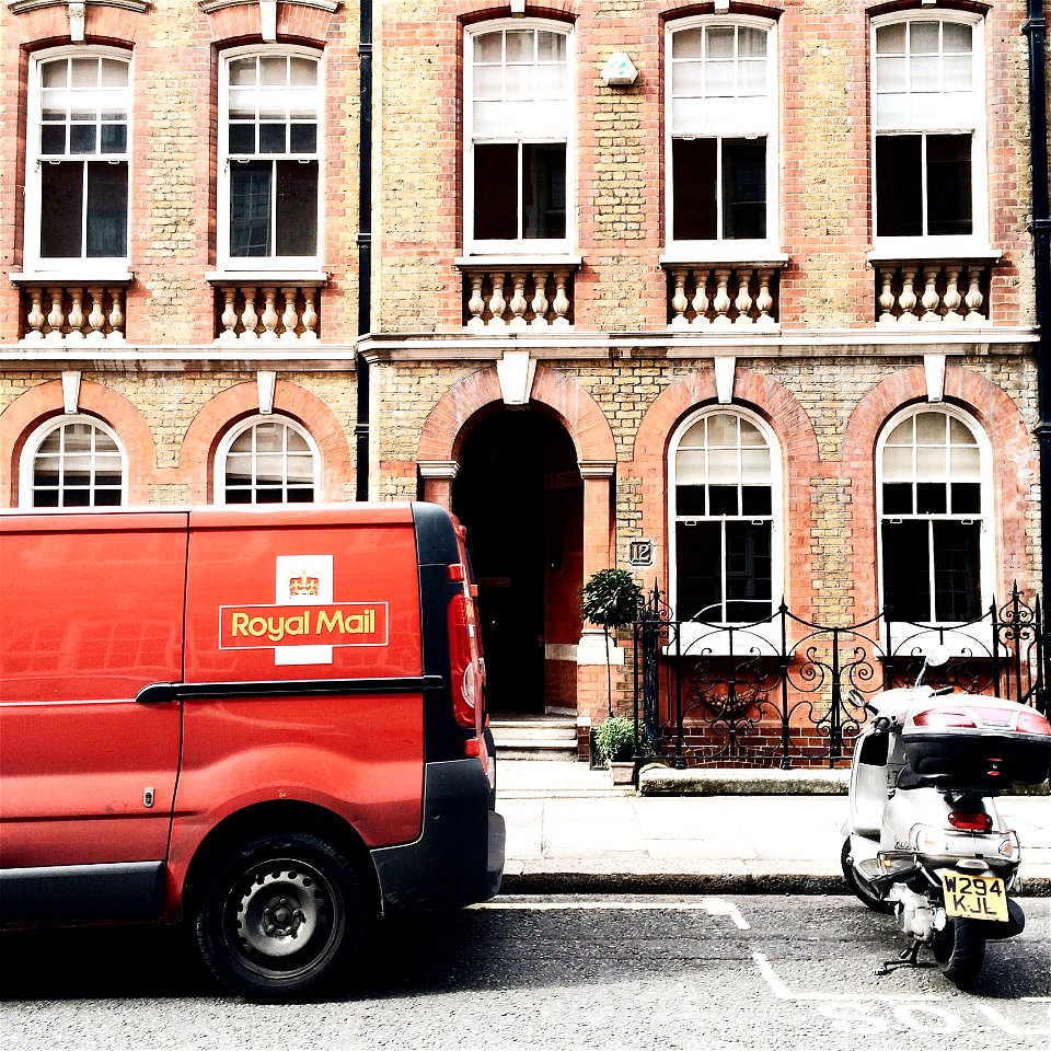 Red Royal Mail Parked Near Brown Brick Building photo