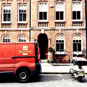 Red Royal Mail Parked Near Brown Brick Building photo