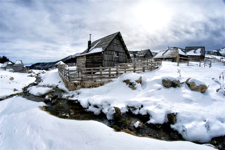 Black Wooden House Surrounded By Snow Under White Clouds