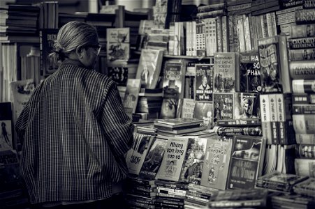 Person Standing In Front Of Assorted Books In Gray Scale Photography