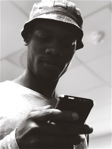 Man In Bucket Hat Holding Black Smartphone photo