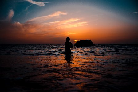 Silhouette Of Woman On Ocean During Sunset photo