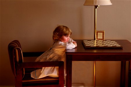 Child Setting On Chair In Front Of Table photo