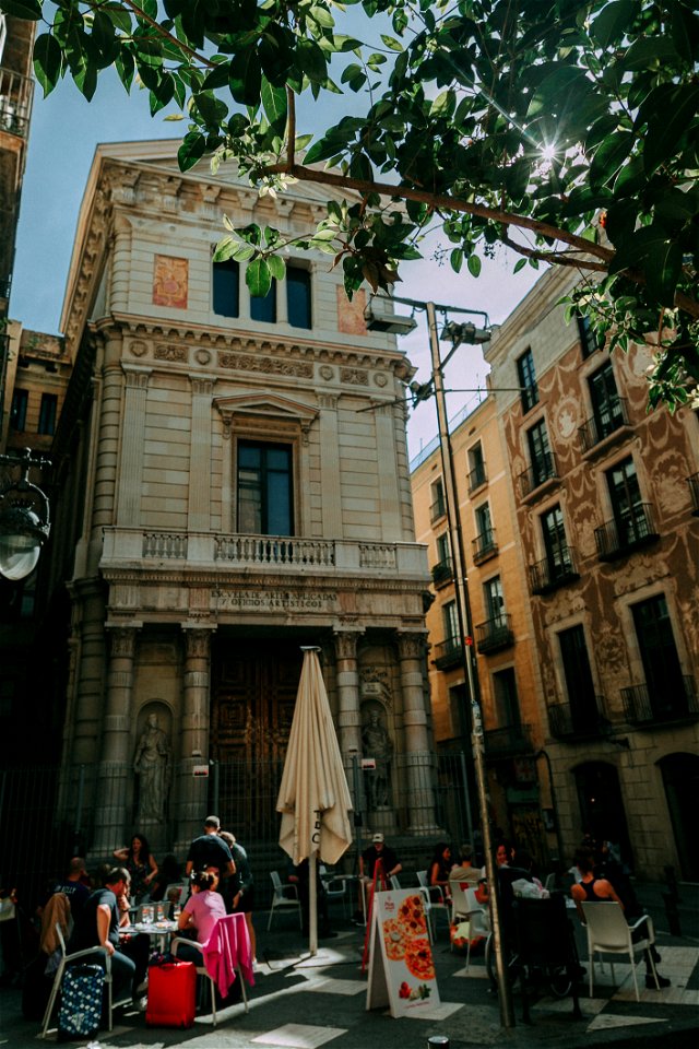 Brown Concrete Building With People Sitting On Patio Sets Photo Taken