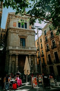 Brown Concrete Building With People Sitting On Patio Sets Photo Taken photo