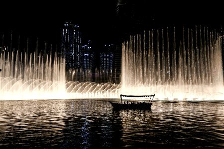Silhouette Of A Boat On A Body Of Water With Fountain
