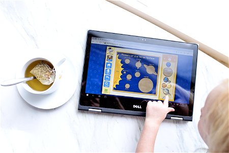 Kid Using Black Dell Tablet With Tea photo