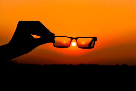 Silhouette Of Persons Hand Holding Eyeglasses During Golden Hour