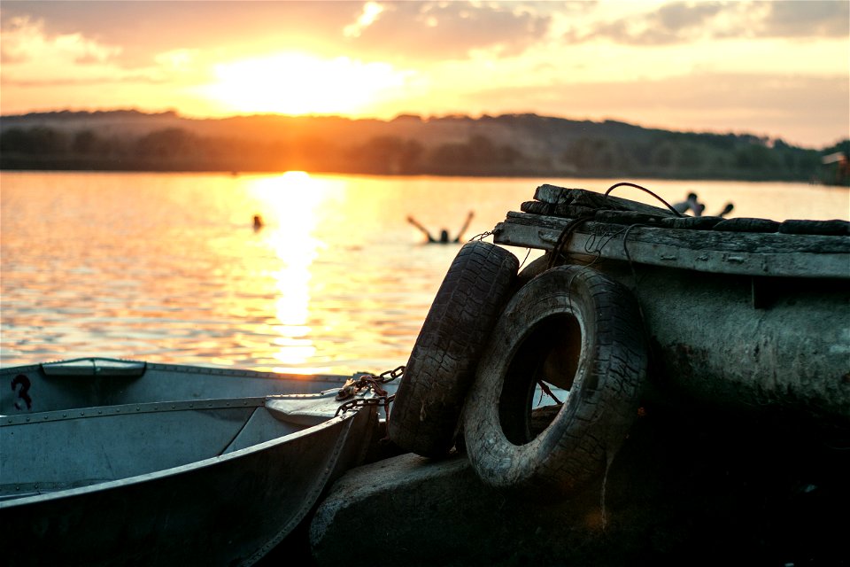 White Boat On Dock Near Two Auto Tires During Sunset