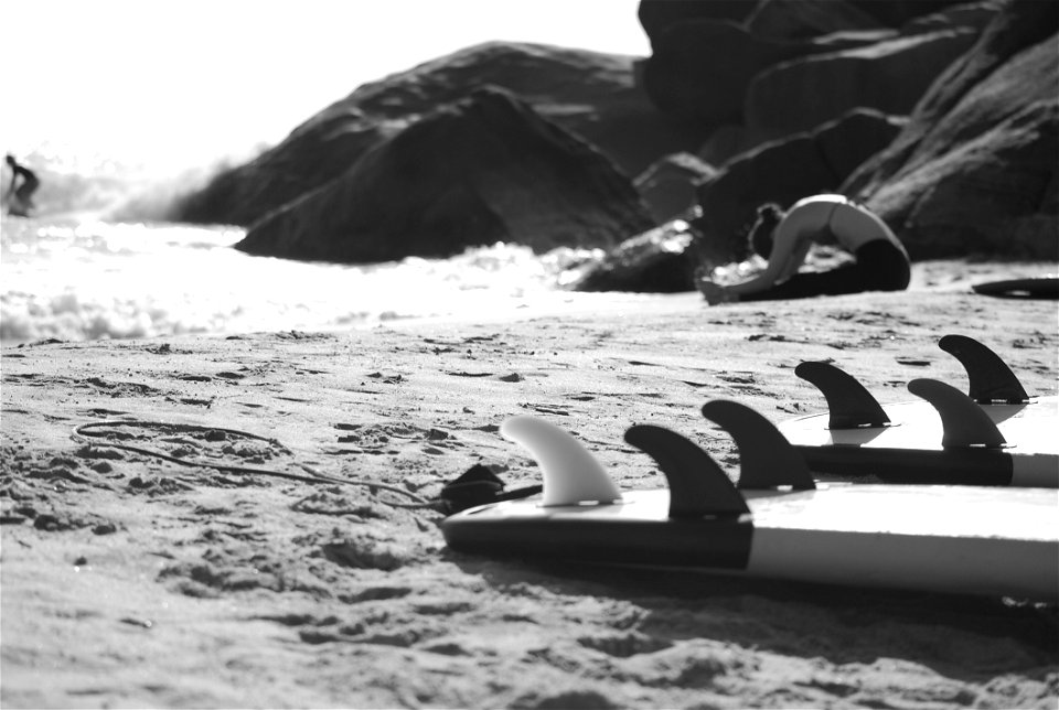 Grayscale Photo Of Woman Sitting On Beach Near Rock Formation photo