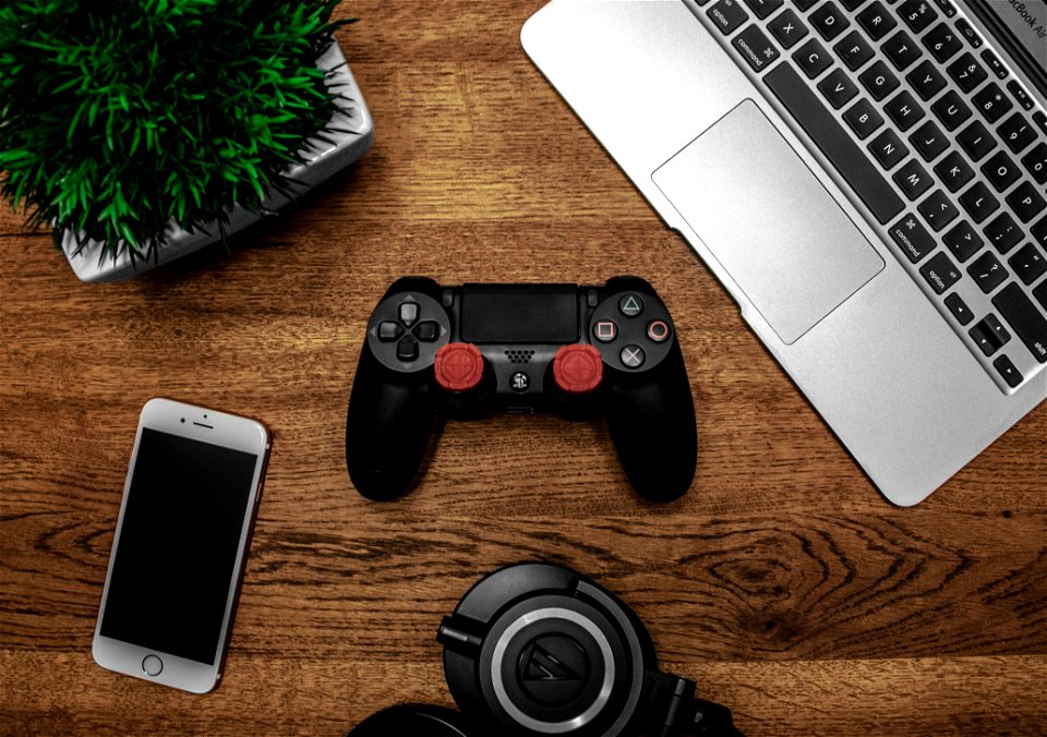Silver Macbook Beside Black Sony Ps4 Dualshock 4 Silver Iphone 6 And Round Black Keychain On Brown Wooden Table
