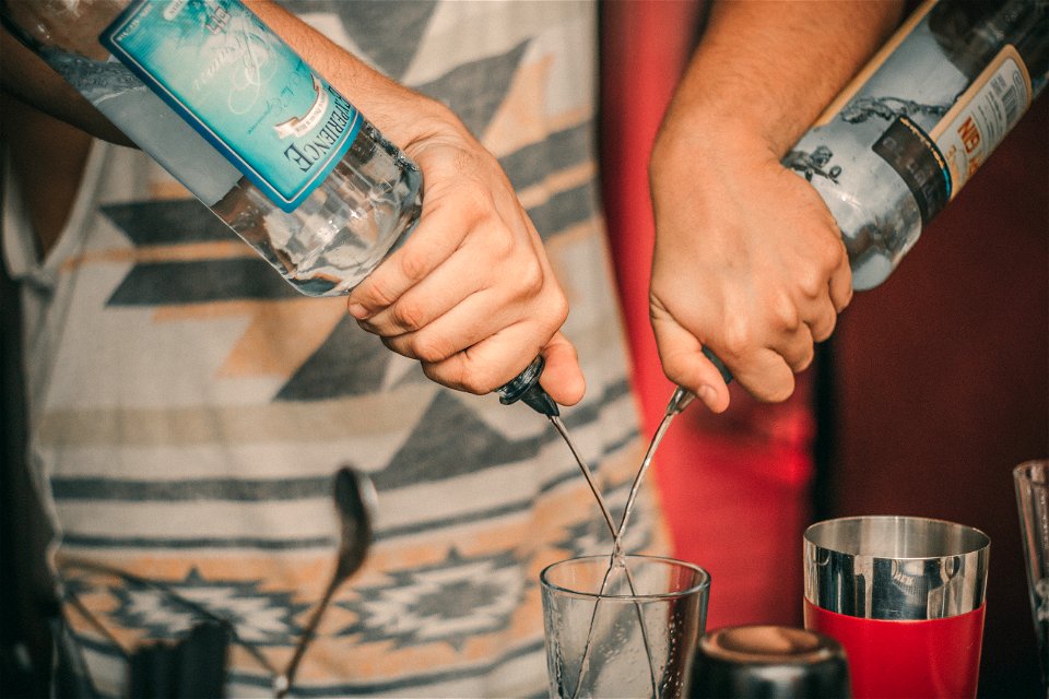 Person Holding Two Soda Bottles With Drinking Glass Below photo