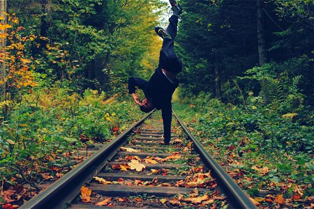 Man Standing With His Right Hand On The Train Rails In Middle Of Forest photo