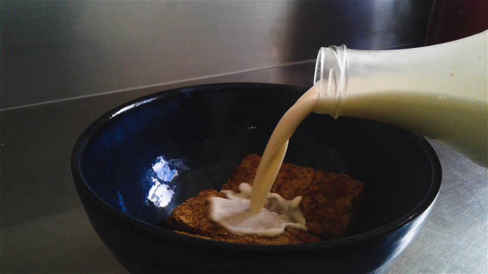 Milk Being Poured In Blue Ceramic Bowl With Cookies photo